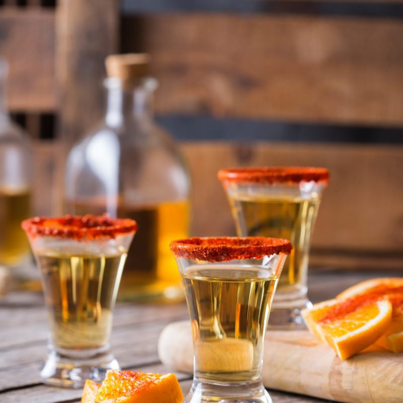 Mexican mezcal or mescal shot with chili pepper and slice of orange. Typical alcohol beverage made from all types of agave unlike tequila in mexico
